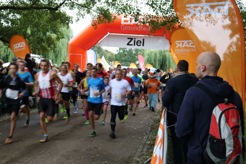 DAK Firmenlauf mit vielen Menschen, die durch ein Ziel laufen