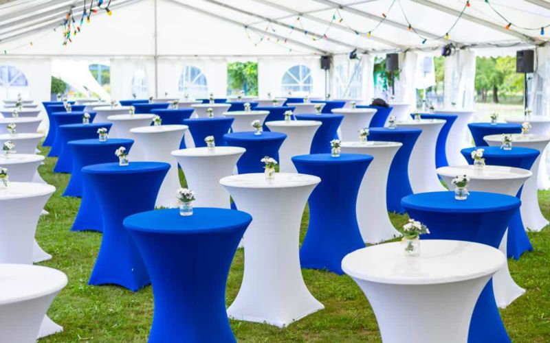 Schön blau und weiß dekorierte Stehtische in einem großen Festzelt